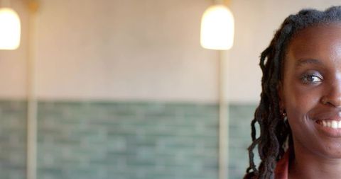 African american woman smiling in cafe with green subway tiles and warm pendant lights