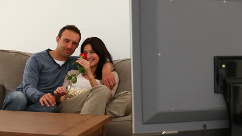 Romantic Couple Sharing a Tender Moment on Sofa with Red Rose
