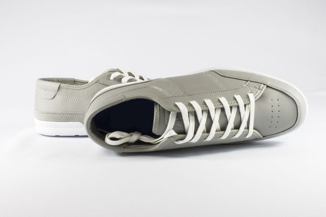 Modern gray leather sneakers with white laces shown from different angles, placed on a white background. These casual shoes feature a minimalistic and trendy design suitable for both men and women. Ideal for fashion blogs, online stores, footwear advertisements, and style magazines focusing on casual and summer fashion.