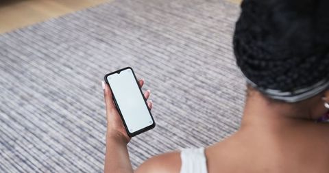 African american woman holding smartphone with blank screen