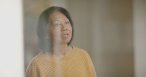 Senior asian woman contemplating in minimalist interior