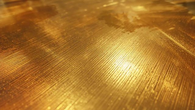 Brushed golden metal panel reflects warm studio light