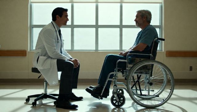 Doctor consulting senior patient in wheelchair in hospital corridor, compassionate care
