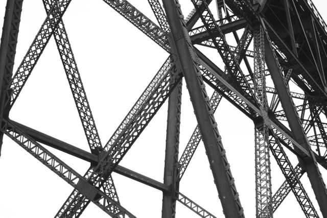 Detailed view of the steel framework of a large bridge, showcasing the intricate construction and engineering involved. The robust support beams and geometric patterns effectively convey the strength and stability of the structure. Ideal for use in architecture and engineering projects, educational materials, or exhibits highlighting industrial marvels. Also suitable for backgrounds and design projects that emphasize industrial aesthetics.