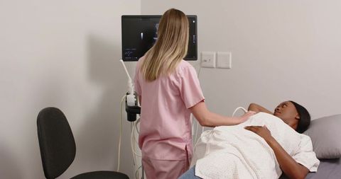Clinician performing abdominal ultrasound on patient in clinic using modern sonography monitor