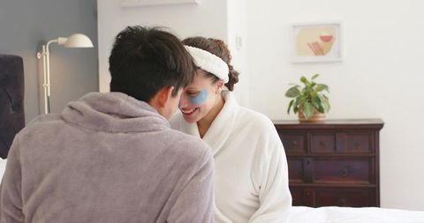 Couple leaning foreheads smiling with blue eye patches cozy intimate morning