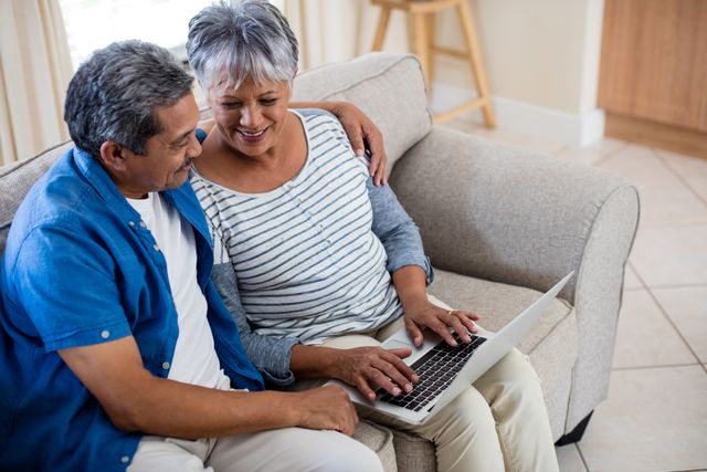 Senior couple using laptop in living room at home