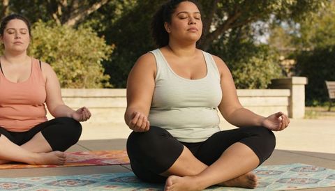Plus-size woman practicing outdoor meditation on patterned mat for mindfulness and wellness