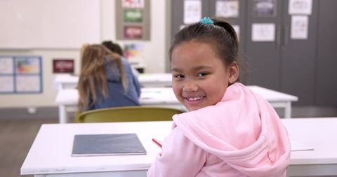 Smiling Schoolgirl in Classroom Turning to Camera in Hoodie