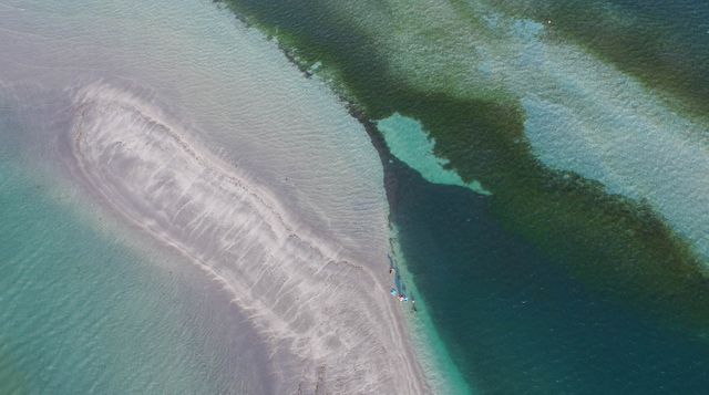 High-angle view reveals a sandbar jutting into the turquoise ocean, emphasizing natural coastal formations. Perfect for travel, tourism, and nature-themed projects or to highlight coastal geology and marine science subjects.