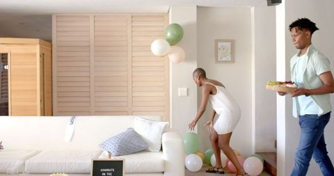 Friends Preparing for Surprise Celebration with Balloons Indoors