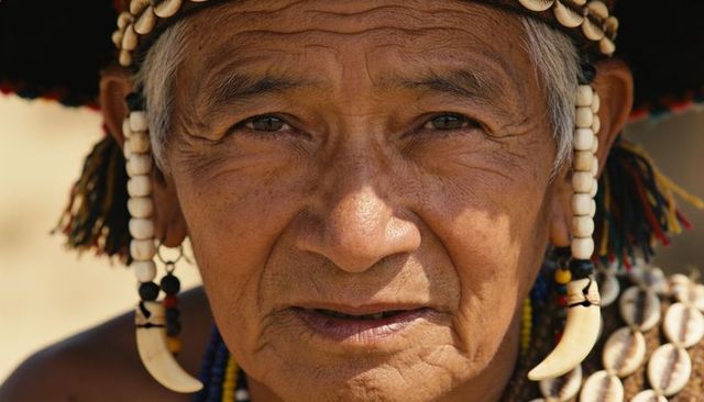 Sunlit elder wearing beaded headdress, shell necklaces and tusk pendants close-up portrait