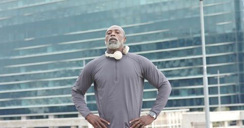 Mature african american athlete standing confident in urban plaza wearing headphones