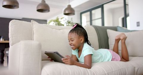 Happy Young Girl Enjoying Educational Tablet Time on Sofa