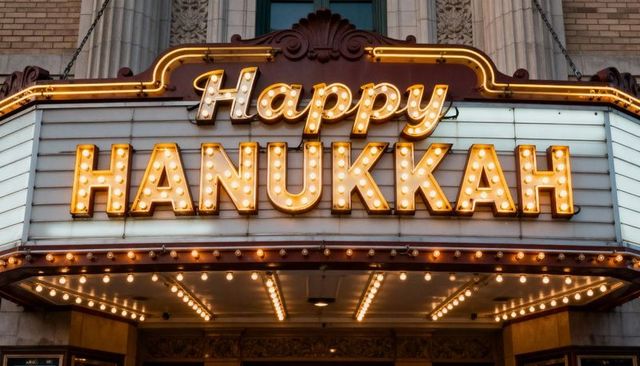 Vintage theater marquee happy hanukkah sign with lit bulbs and historic facade at night