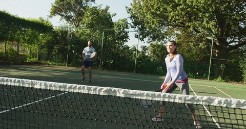 Joyful Couple Playing Tennis in Sunlit Outdoor Court - Download Free Stock Images Pikwizard.com