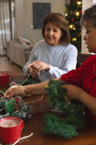 Middle-aged Women Crafting Christmas Wreaths in Cozy Living Room Setting