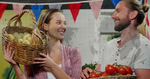 Smiling farmers market vendors holding baskets of fresh potatoes and tomatoes