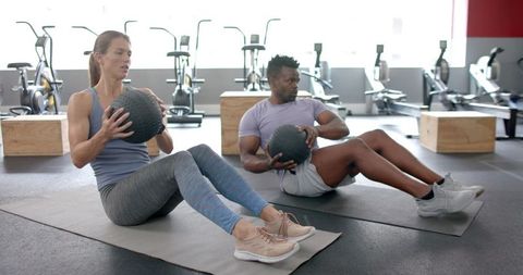 Focused diverse athletes engaging in medicine ball workout at gym