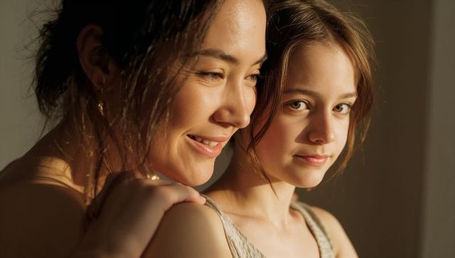 Mother and teenage daughter sharing warm sunlight and gentle embrace in home portrait