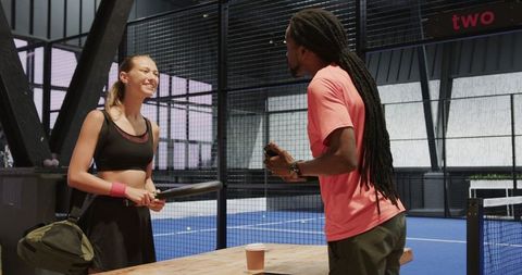 Tennis Player Discussing Techniques with Coach on Indoor Court