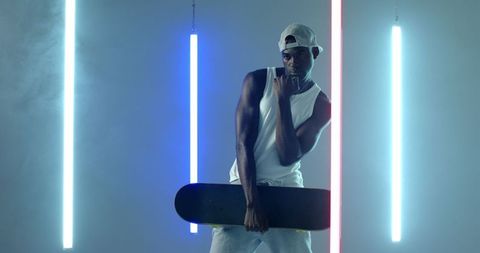 Urban Style: Man Posing with Skateboard and Neon Lights