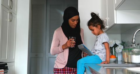 Mother and daughter interacting with tablet app in kitchen
