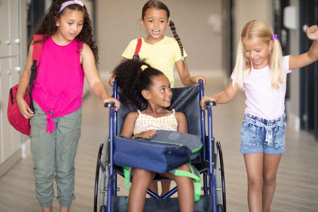 Multiracial elementary schoolgirls are helping their African American classmate in a wheelchair. This image highlights themes of diversity, inclusion, and friendship among young students. It can be used for educational materials, disability awareness campaigns, and promoting inclusive environments in schools.