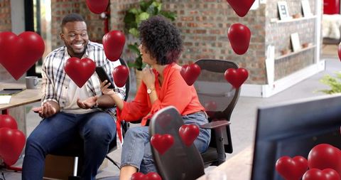 Coworking Colleagues Sharing Laughs and Digital Valentines in Casual Modern Workspace