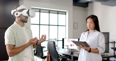 Man Using VR Headset While Woman Holds Tablet in Modern Office