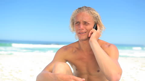 Serious Man Having Phone Call on Sunny Beach Day