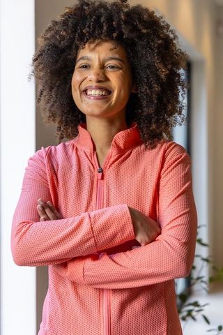 African american woman smiling in coral athletic jacket standing arms crossed confidently