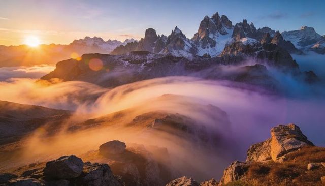 Sunrise fog flowing over alpine ridge with jagged snowy peaks and golden light