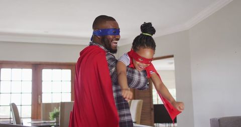 Father and Daughter in Superhero Capes Playing at Home