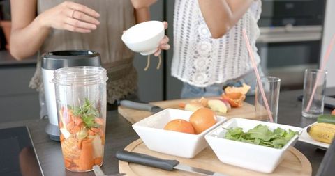 Women Preparing Healthy Smoothie with Fresh Ingredients in Modern Kitchen