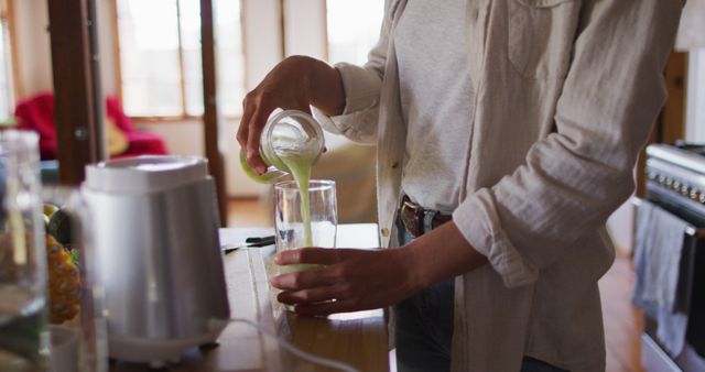 Woman Pouring Green Smoothie into Glass in Bright Kitchen - Download Free Stock Images Pikwizard.com