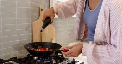 Person Cooking Vegetables in Wok on Gas Stove