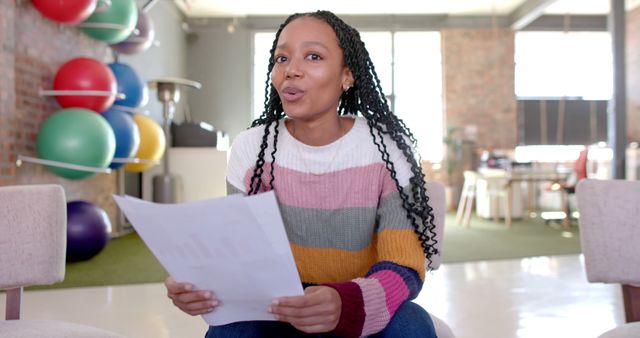 Confident Woman in Striped Sweater Holding Documents in Modern Office - Download Free Stock Images Pikwizard.com