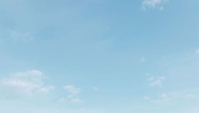 Expansive clear blue sky with scattered wispy clouds, minimal calm background for design