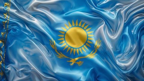 Glossy blue silk kazakhstan flag featuring golden sunburst and steppe eagle emblem
