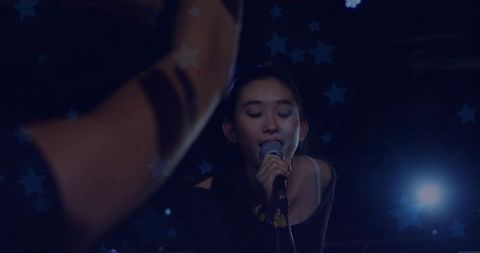 Chinese singer performing on dark stage with microphone