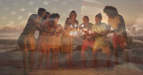 Friends with sparklers celebrating on beach at sunset