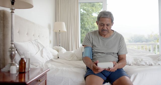 Senior Man Monitoring Blood Pressure at Home, Sitting on Bed - Download Free Stock Images Pikwizard.com