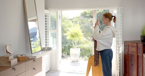 Woman contemplating outfit choice at home, natural light