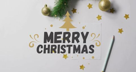Merry christmas bold typography on minimalist white flatlay with gold stars and ornaments