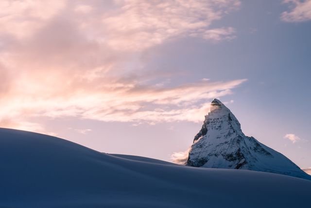 Dramatic snow-covered mountain peak gleaming in morning light, surrounded by scenic winter landscape. Ideal for travel imagery, nature blogs, outdoor adventure promotions, or inspirational posters.