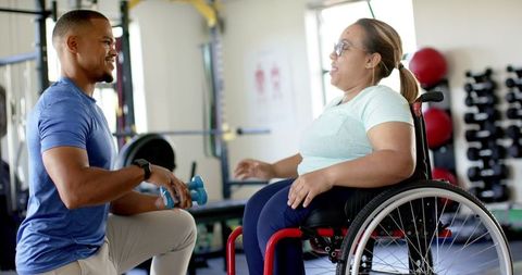 Physical Therapist Assisting Wheelchair User with Exercises in Gym
