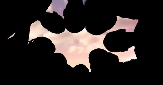 Digital composite of Silhouette children making huddle against sky