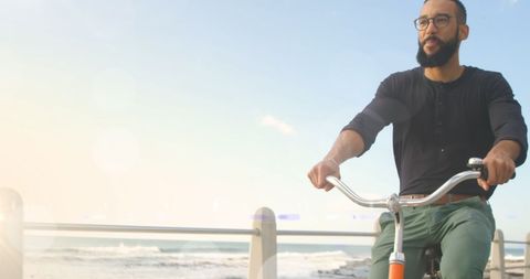 Man Cycling by Ocean on Sunny Day