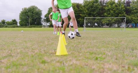 Teenagers practicing dribbling skills in soccer drills on field